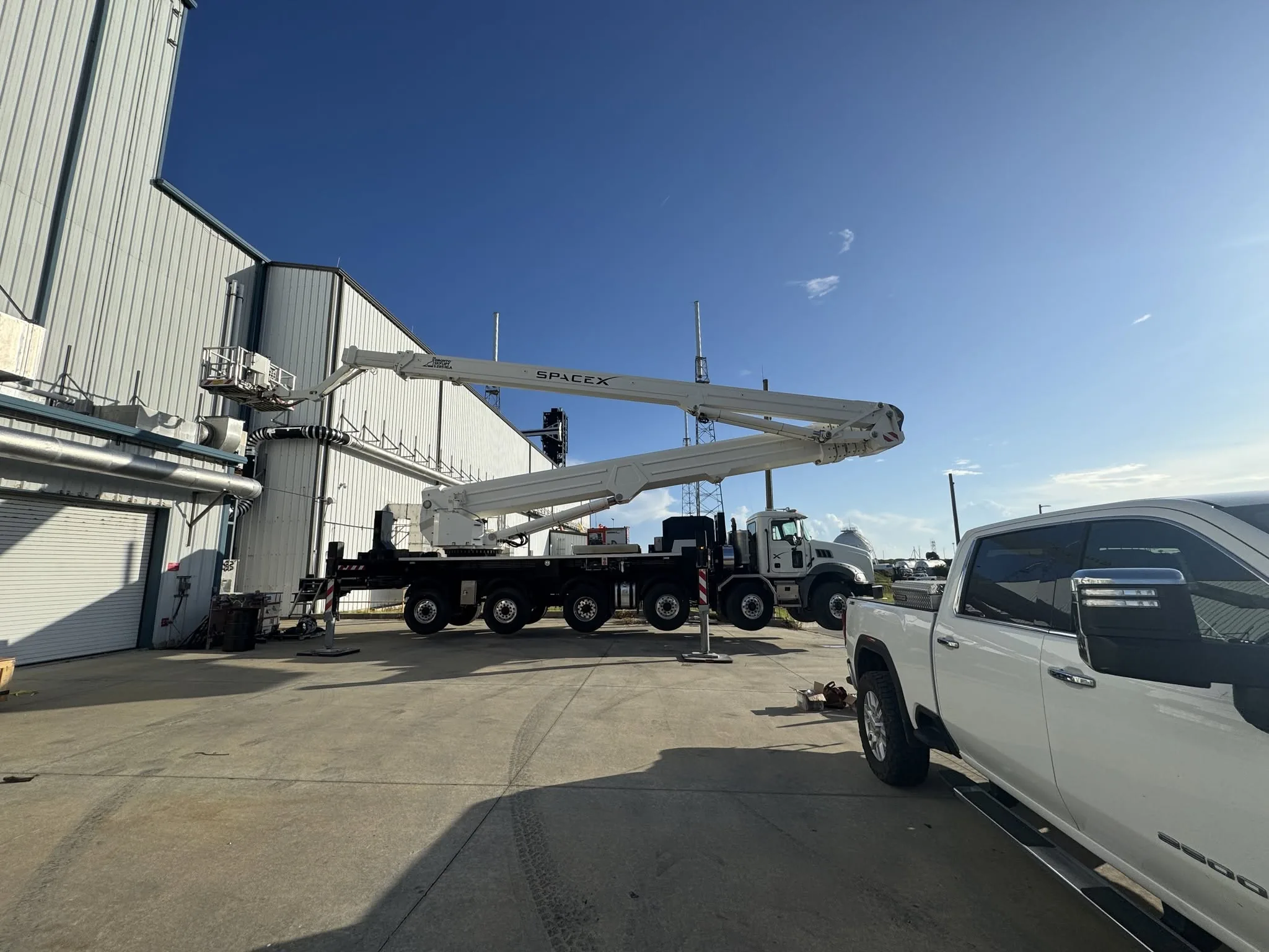 Aerial boom truck extended at a waterfront commercial job site.