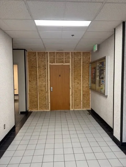 Finished commercial hallway with tile flooring and wood-tone door.