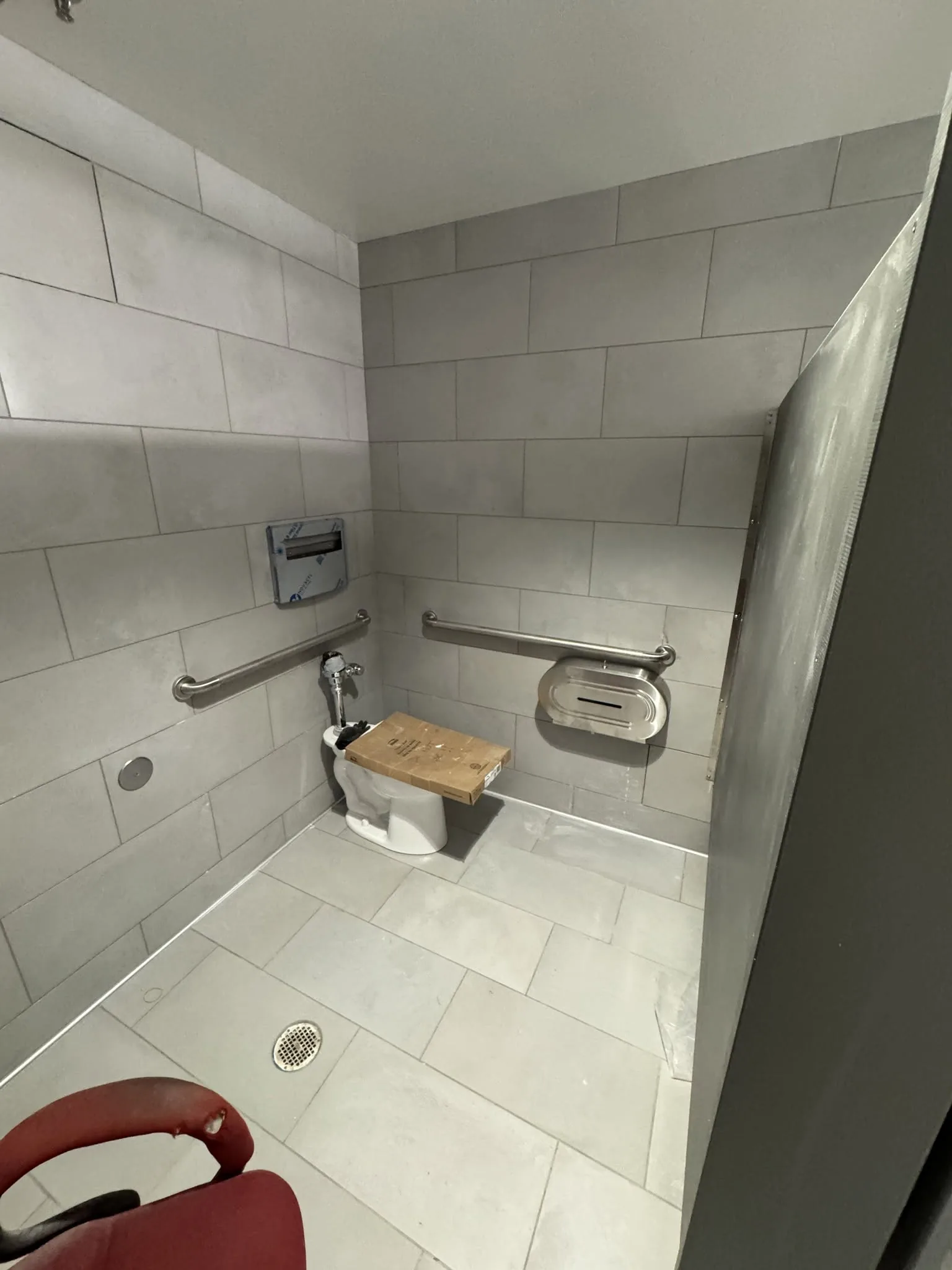 Accessible restroom stall with grab bars and floor-mounted fixtures.