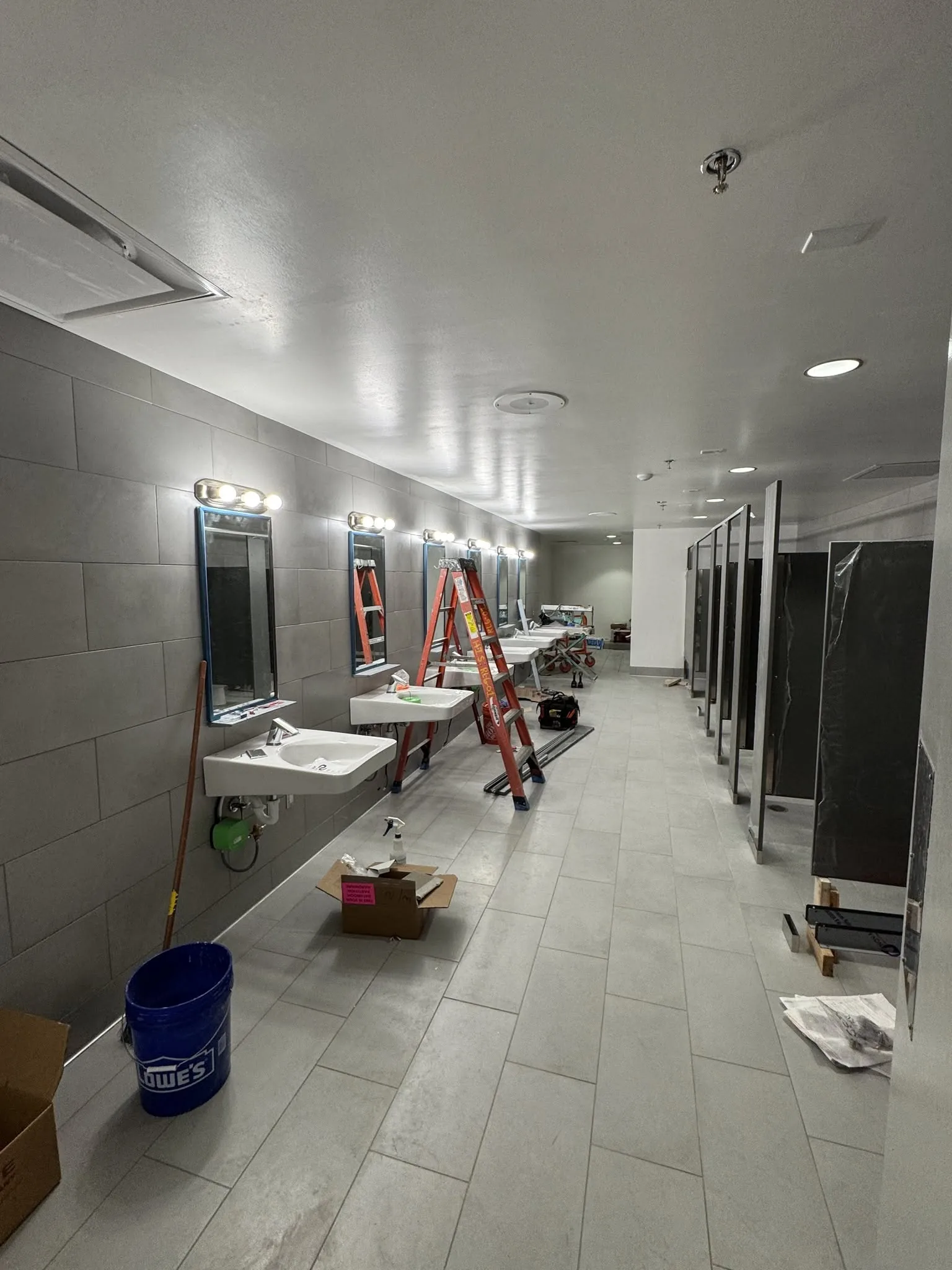 Commercial restroom stall partitions being installed during a buildout.