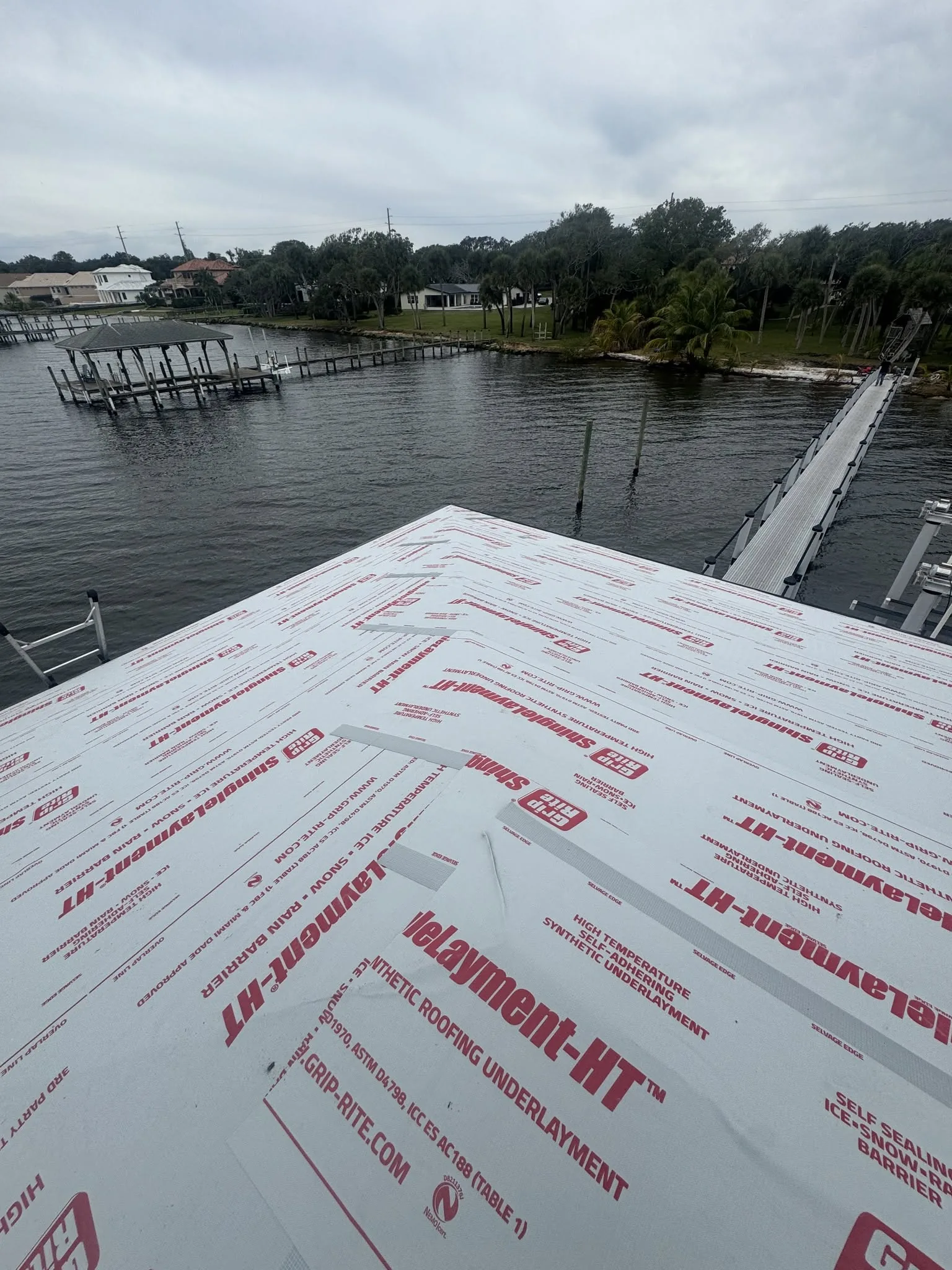 Roofing underlayment being installed on a sloped roof during construction.