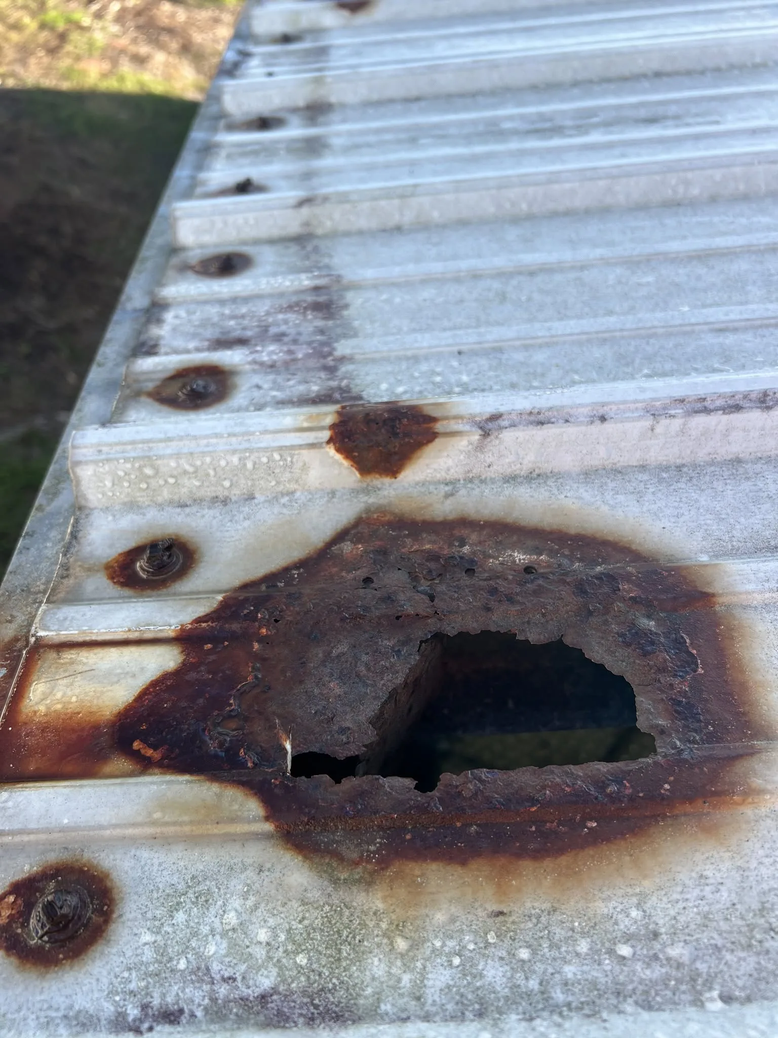Close-up of corroded and damaged metal roofing panel before replacement.