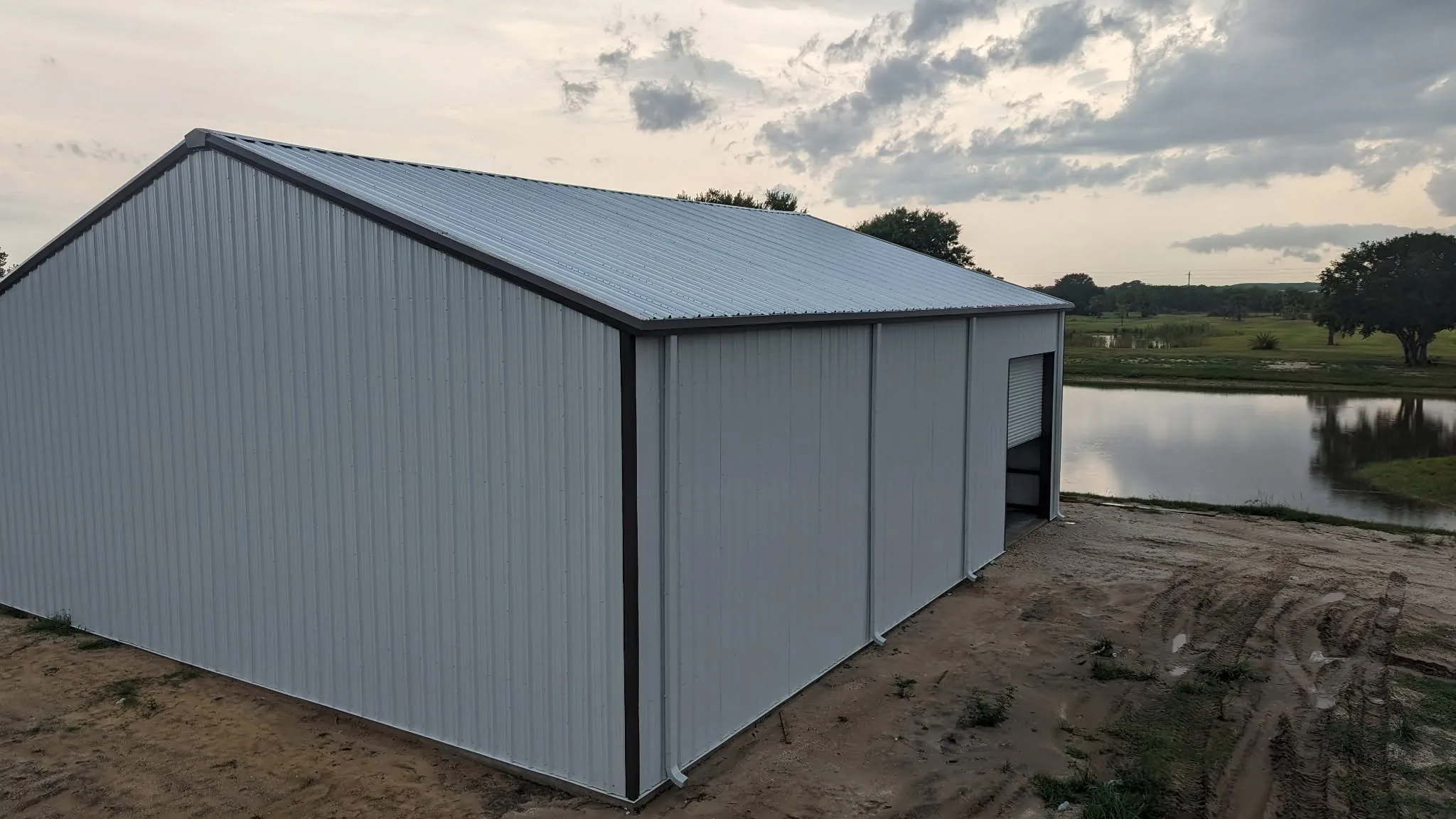 Steel building exterior nearing completion with graded site work visible.